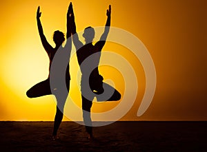 Two people practicing yoga in the sunset light