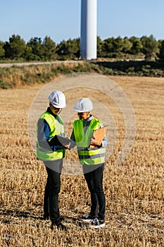 Two people in protective work clothing and reflective garments working together.