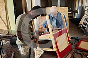 Two people repairing furniture working in carpentry workshop together