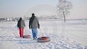 Two people ride on a snowy hill on a sled. A man and a girl climb to the top of the mountain. Walks in the fresh air