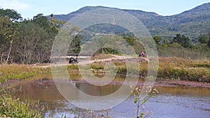 Two People Riding A All-Terrain Vehicle ATV In The Valley .