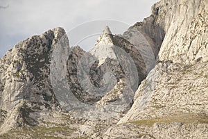 two people are riding horseback past a mountain range with rocks