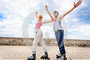 Two people on rollerblades with spread arms.