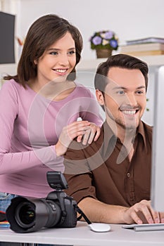 Two people are seating by computer. photo