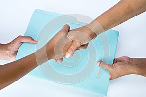 Two people shaking hands and exchanging documents as a sign of agreement