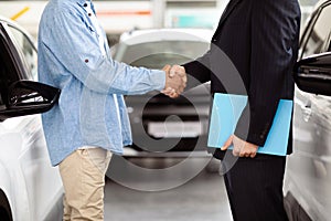 Two People Shaking Hands in Front of a Car