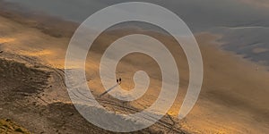 Two people on the shore of Blacks Beach at sunset