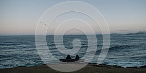 two people sitting on bench watching ocean peacefully