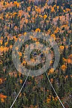 two people sliding down very long and fast zipline during autumn in Stowe, Vermont