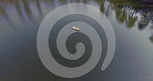 Two people in the small boat boating across a beautiful wide reflective lake or river. Active lifestyle, connection with