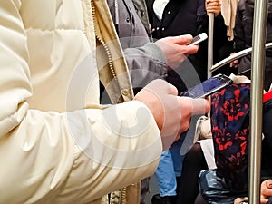 Two people with smartphones in hands in a subway train, going to work