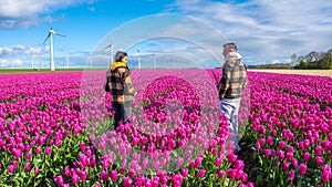 Two people standing gracefully in a vibrant field of purple tulips, surrounded by the beauty of nature in full bloom photo