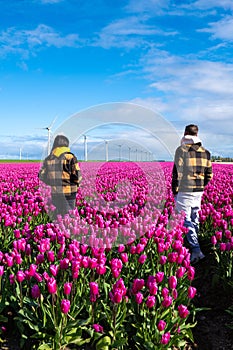 Two people standing joyfully in a field of vibrant purple tulips, surrounded by the beauty of Spring in the Netherlands