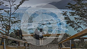 Two people are standing on the observation deck at the Perito Moreno glacier