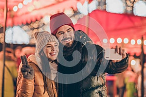 Two people students friends take selfie on cellphone girl make v-sign on outdoors x-mas christmas town event