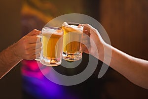 Two people toasting with mugs full of chopp