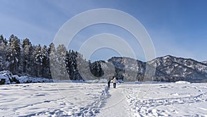 Two people walk away along a path trodden in the snow.