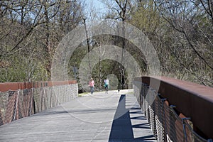 Two People walk a dog over the Wolf River bridge.