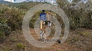 Two people are walking along a dirt path.