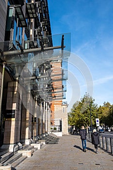 Two People Walking Past The Main Entrance Of Portcullis House Govenrment Office Building Victoria Embankment