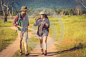 Two people walking on path in meadow field. Male and female traveler looking at attraction view point. Couples adventure at