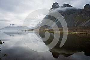 Two people walking towards cars on Hvalnes peninsula on the Southcoast of Iceland.