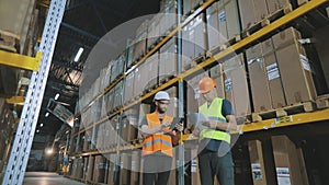 Two people in the warehouse are discussing something. Two Engineers in a modern warehouse.