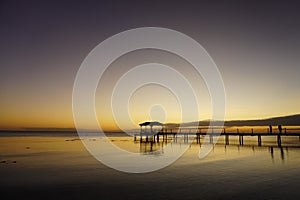 Two people watch a sunset from a pier leading into a lagoon on the island of Fakarava in French Polynesia photo