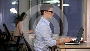 Two people working on laptop in big office, technical support, service center