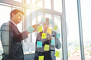 Two person coworker young asian businessman in formal dress communication on posit on wall in modern workplace