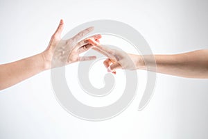 Two person playing rock paper scissors; one hand showing paper symbol and another hand showing scissors symbol; concept of