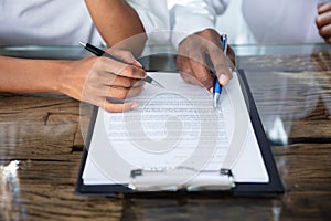 Two Person`s Hand Reviewing Contract Form