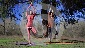 Two persons doing couple yoga namaste pose on the beach at sunset