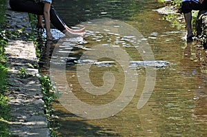 Two persons having their feet in a river to cool down