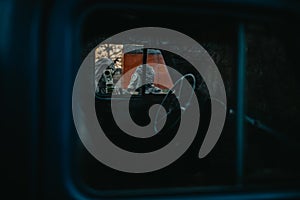 Two persons in NBC protective suits and gas masks, view through cabin of old truck