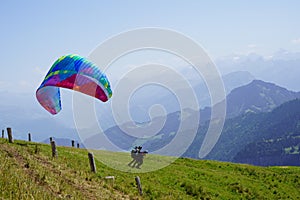 Two persons running to launch a paraglide and catch air current.