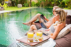 Two persons using tech gadgets by the pool