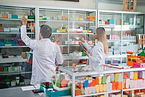 two pharmacists in uniform composing medicine on a display case