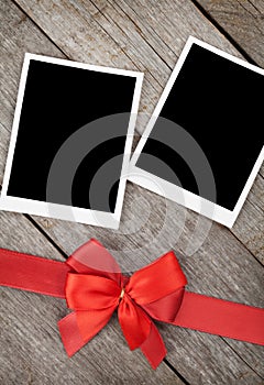 Two photo frames over wooden background with red bow