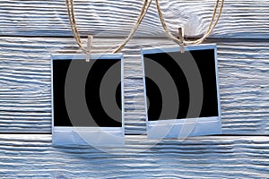 Two photo frames on ropes and wooden wall background