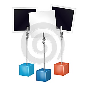 Two photo frames and white note on a metal memo holder clip. Photos and memories card on wire silver clamps over white background