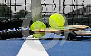 Two pickleball paddles and two yellow whiffle balls