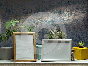 Two picture frame mockups and plants on white shelf against old blue wall