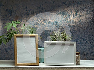 Two picture frame mockups and plants on white shelf against old blue wall