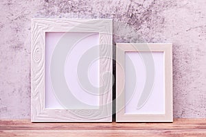 Two Picture frame on wall background and wooden table. Poster product design styled