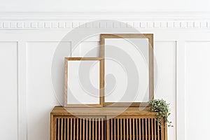 Two picture frames on a wooden sideboard