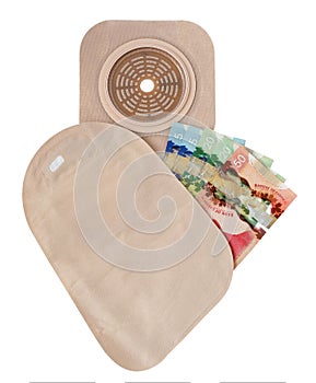 Two piece ostomy appliance including flange, pouch with money isolated a white background.