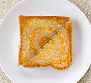 Two piece triangle slices of toasted bread made from white wheat flour and a slice of cheddar cheese in white plate