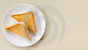 Two piece triangle slices of toasted bread made from white wheat flour and a slice of cheddar cheese in white plate