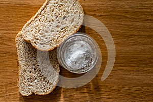 Two pieces of black bran fresh bread with white salt in a salt shaker
